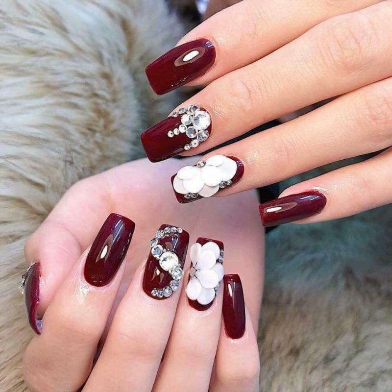 Burgundy nails with white floral embellishments